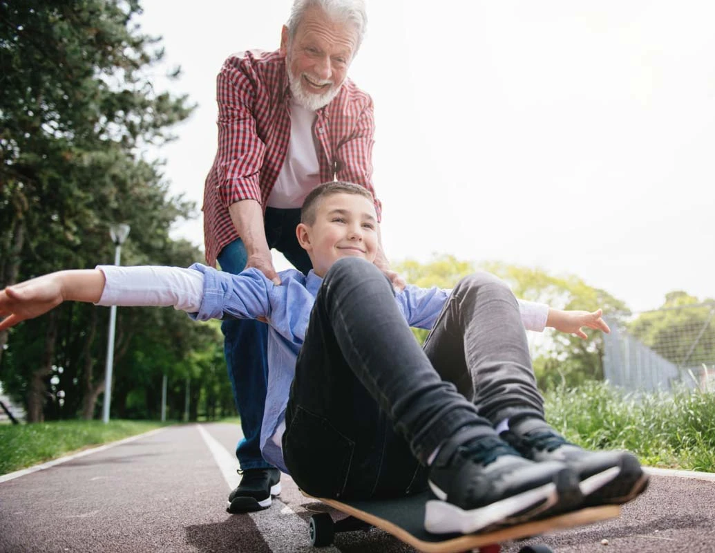 Older man pushing a boy on a skateboard